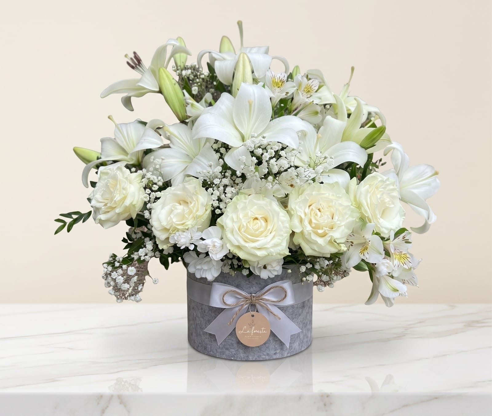 Detalle del arreglo floral Sereno con rosas y lirios en caja gris